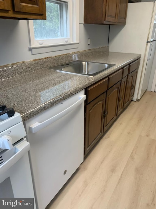 kitchen with white appliances, light hardwood / wood-style floors, dark brown cabinetry, and sink