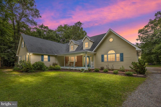 cape cod house featuring a lawn and covered porch