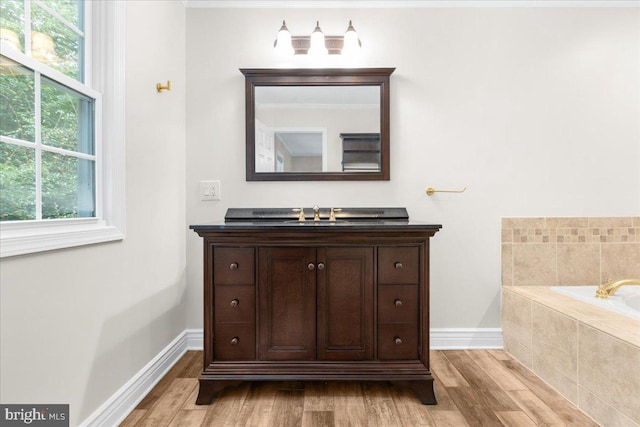 bathroom featuring tiled bath, hardwood / wood-style floors, and vanity