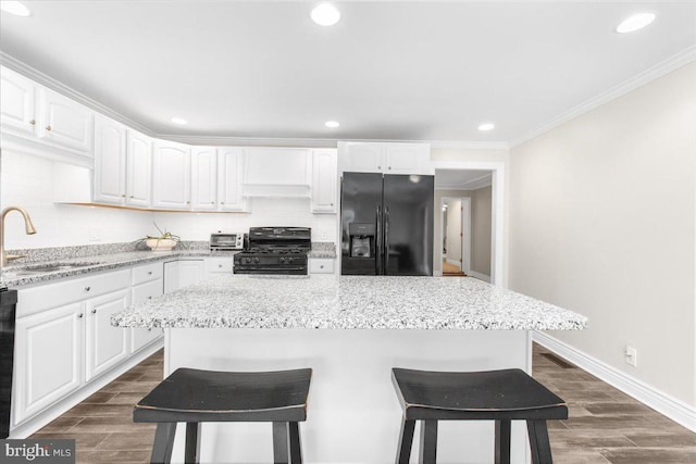 kitchen with black appliances, a center island, white cabinets, and sink