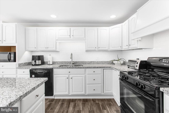 kitchen with light stone countertops, sink, white cabinets, and black appliances