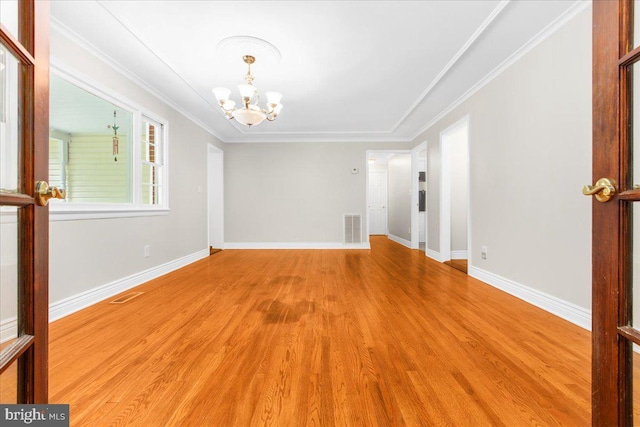 empty room featuring a chandelier, light hardwood / wood-style flooring, and ornamental molding