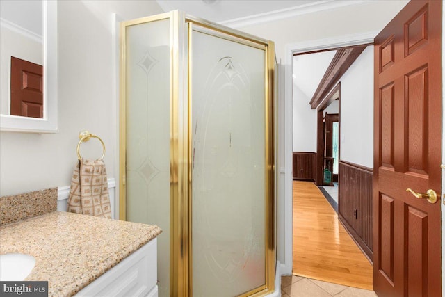 bathroom with an enclosed shower, vanity, crown molding, lofted ceiling, and wood walls