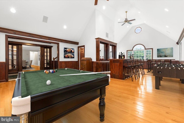 recreation room with hardwood / wood-style floors, high vaulted ceiling, french doors, wooden walls, and ceiling fan