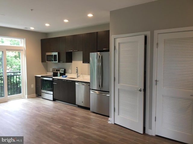 kitchen featuring dark brown cabinetry, appliances with stainless steel finishes, sink, and light wood-type flooring