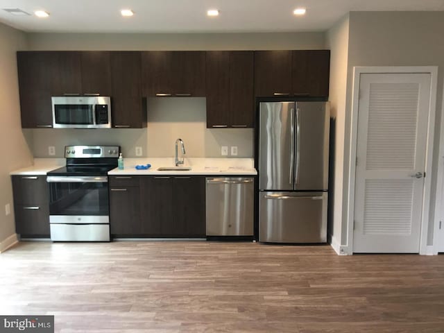 kitchen featuring sink, dark brown cabinets, stainless steel appliances, and light hardwood / wood-style floors