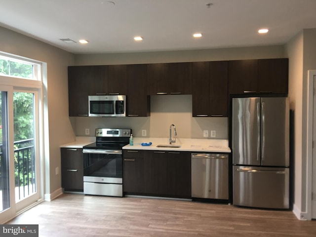 kitchen featuring dark brown cabinetry, stainless steel appliances, sink, and light wood-type flooring