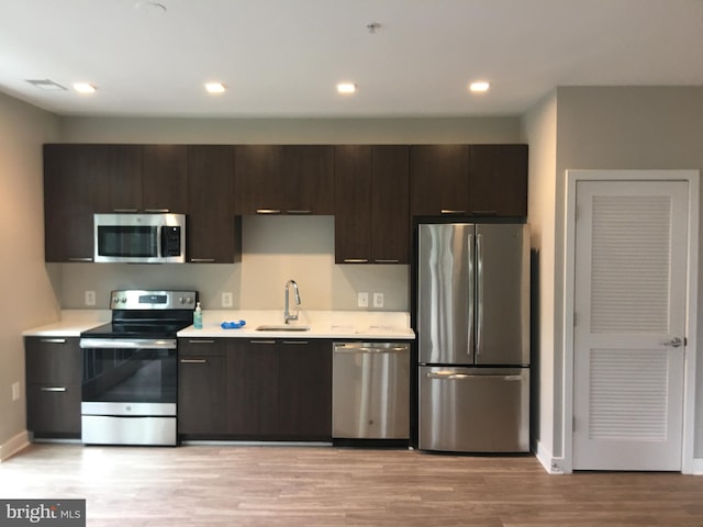 kitchen featuring dark brown cabinetry, stainless steel appliances, sink, and light wood-type flooring