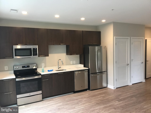 kitchen featuring dark brown cabinetry, sink, light hardwood / wood-style floors, and appliances with stainless steel finishes