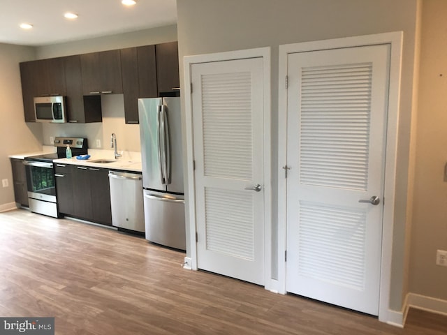 kitchen with dark brown cabinetry, sink, light hardwood / wood-style flooring, and stainless steel appliances