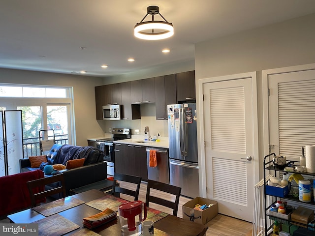 kitchen featuring appliances with stainless steel finishes, sink, light wood-type flooring, and dark brown cabinets