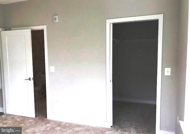 unfurnished bedroom with a walk in closet, carpet floors, and a closet