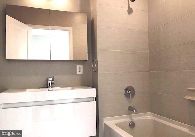 bathroom featuring tiled shower / bath and vanity