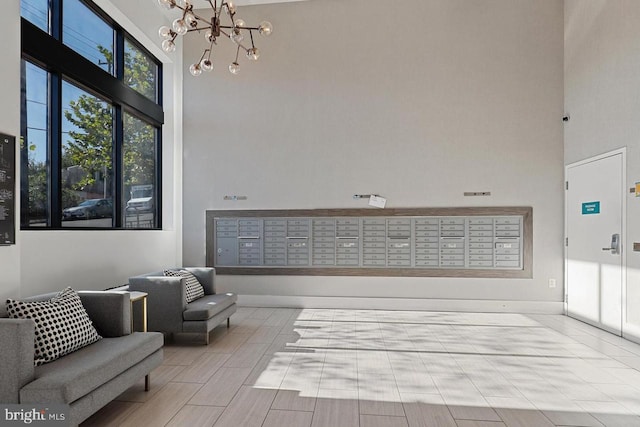 living area with a high ceiling, a mail area, and an inviting chandelier