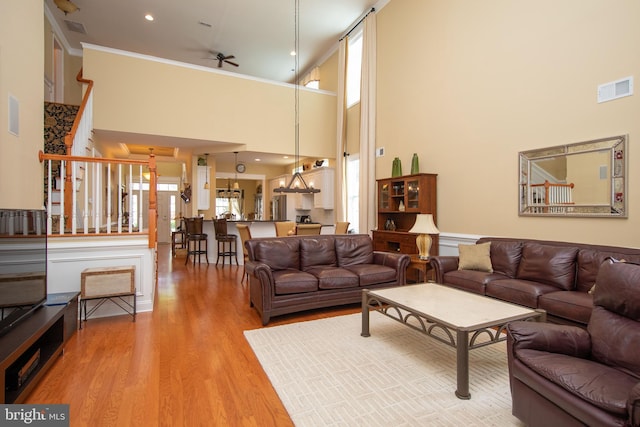 living room featuring wood-type flooring, a towering ceiling, ceiling fan, and a healthy amount of sunlight