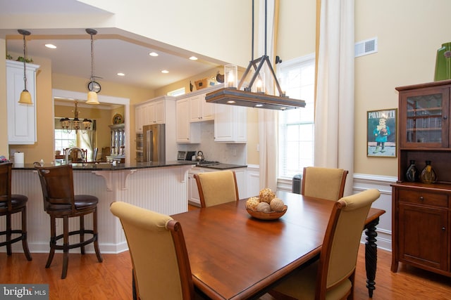 dining area with light wood-type flooring, a notable chandelier, and sink