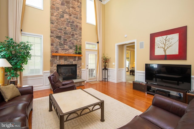 living room with a fireplace, a high ceiling, and light hardwood / wood-style flooring