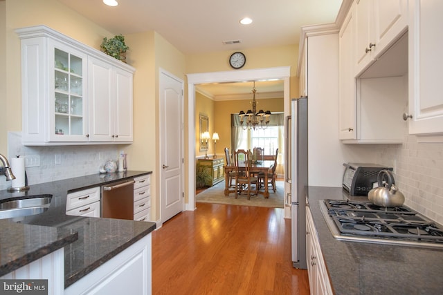 kitchen featuring appliances with stainless steel finishes, dark stone counters, sink, light hardwood / wood-style flooring, and white cabinets