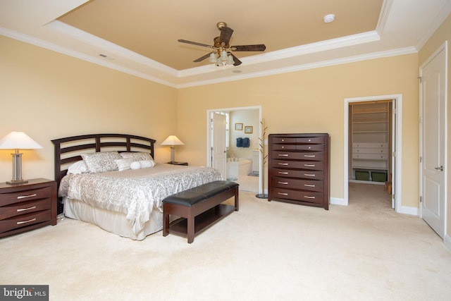 carpeted bedroom with a raised ceiling, ensuite bath, ceiling fan, and crown molding