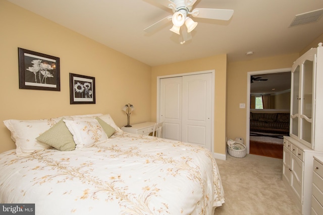 bedroom featuring ceiling fan, light carpet, and a closet