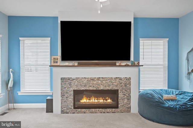 interior space with ceiling fan and a stone fireplace