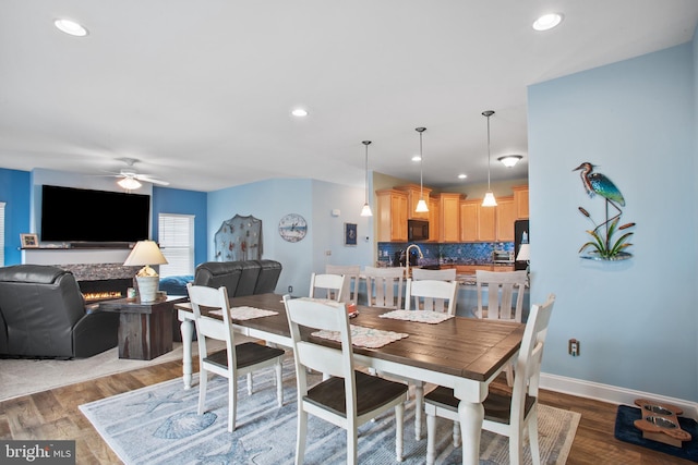 dining area with ceiling fan, a fireplace, and dark hardwood / wood-style floors