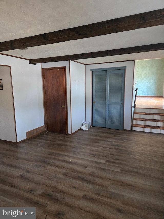 unfurnished bedroom with beam ceiling and dark wood-type flooring