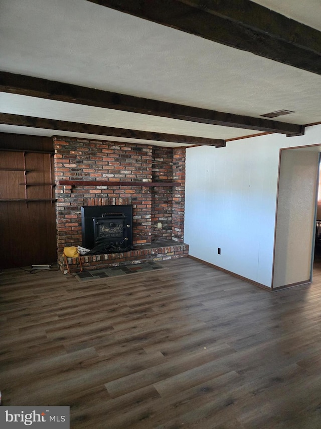 unfurnished living room featuring beamed ceiling, dark hardwood / wood-style floors, a wood stove, and wooden walls