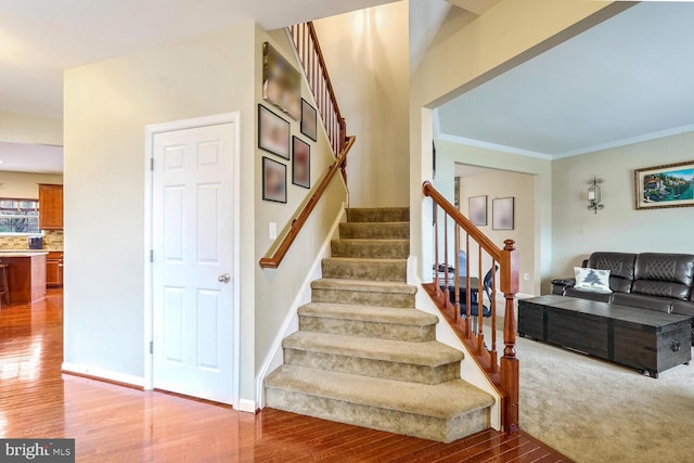 stairs with hardwood / wood-style floors and ornamental molding