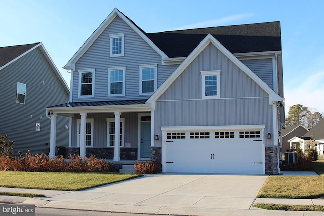 view of front of property featuring cooling unit, a garage, a front lawn, and covered porch