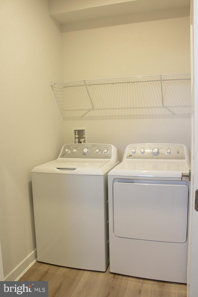 laundry area with washing machine and clothes dryer and wood-type flooring