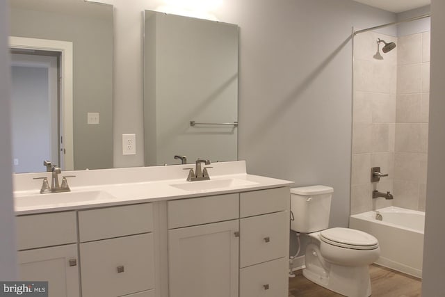 full bathroom with hardwood / wood-style floors, vanity, tiled shower / bath, and toilet