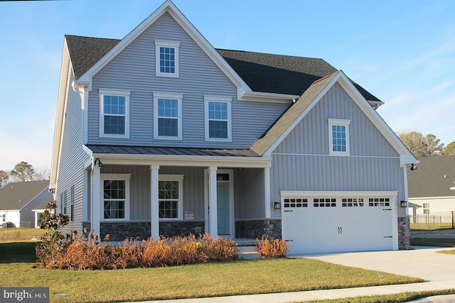 view of front of property featuring a garage, a front lawn, and covered porch