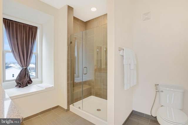 bathroom featuring tile patterned floors, toilet, and a shower with shower door