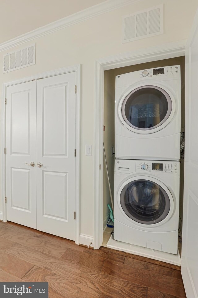 washroom featuring stacked washing maching and dryer and light hardwood / wood-style floors