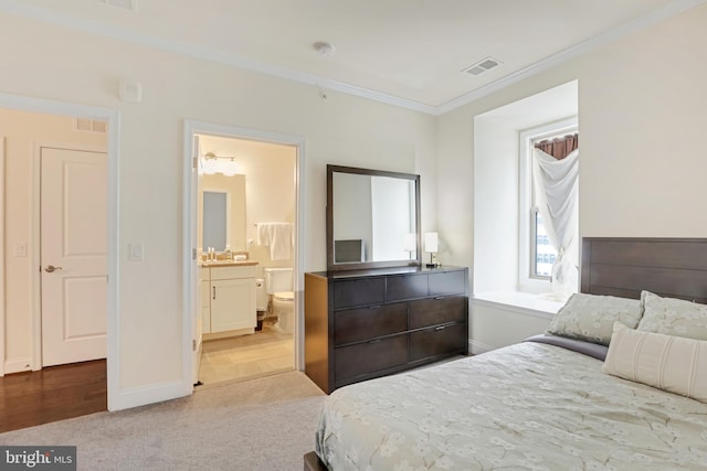 bedroom with light carpet, sink, ensuite bathroom, and ornamental molding