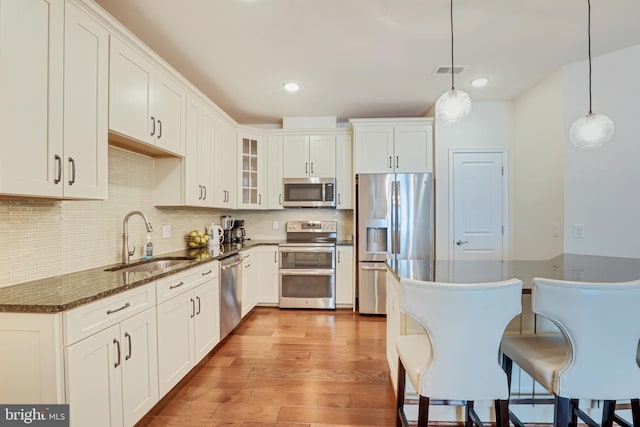 kitchen with white cabinets, decorative light fixtures, stainless steel appliances, and sink