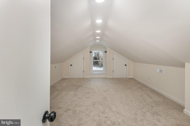 bonus room with light carpet and vaulted ceiling