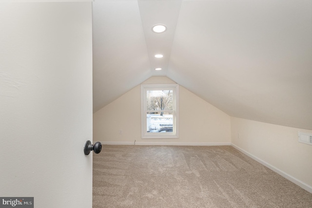 additional living space featuring light carpet and vaulted ceiling