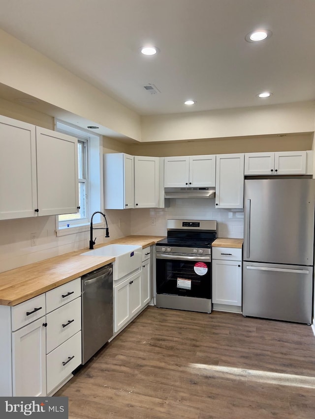 kitchen featuring wooden counters, white cabinets, stainless steel appliances, and light wood-type flooring