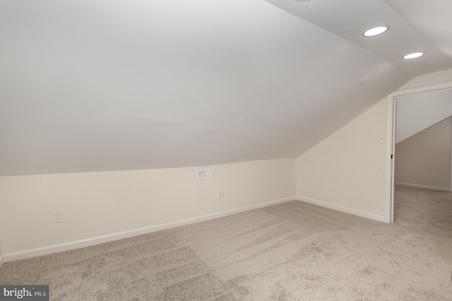 bonus room with light carpet and vaulted ceiling