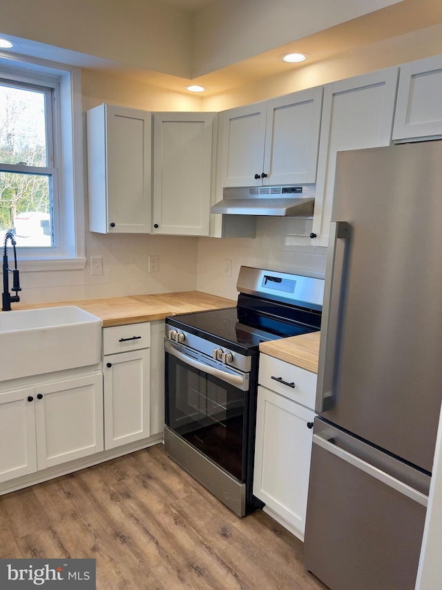 kitchen with wooden counters, stainless steel appliances, sink, light hardwood / wood-style floors, and white cabinetry