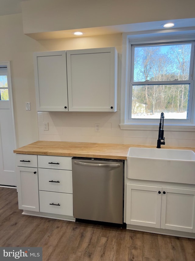 kitchen with stainless steel dishwasher, white cabinetry, sink, and wooden counters