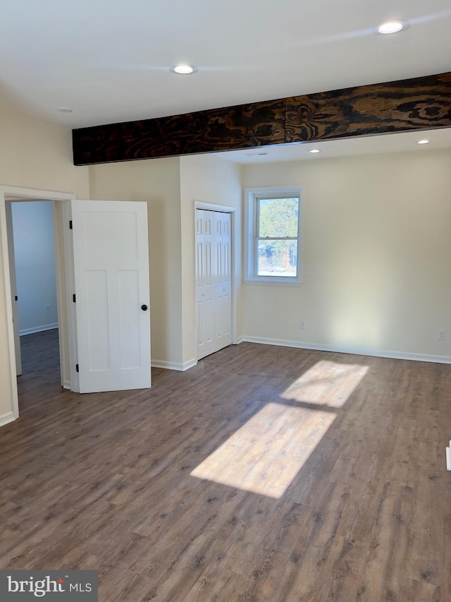 spare room featuring beam ceiling and hardwood / wood-style flooring