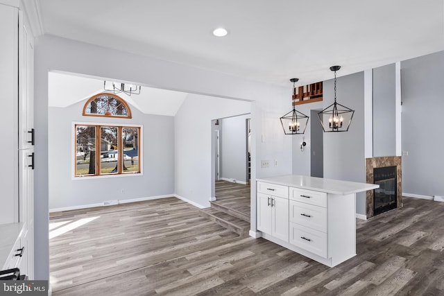 interior space featuring white cabinets, a premium fireplace, pendant lighting, and dark hardwood / wood-style floors