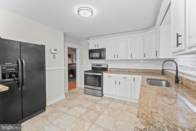 kitchen featuring light stone counters, sink, white cabinets, and black appliances