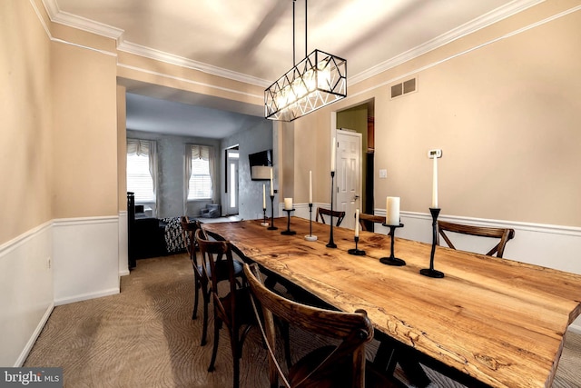 carpeted dining room with ornamental molding