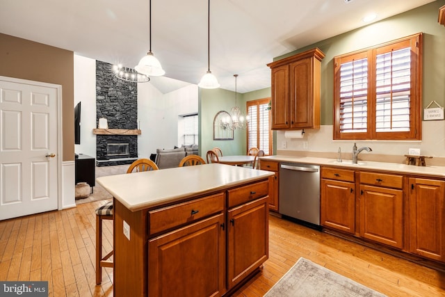 kitchen with pendant lighting, dishwasher, a stone fireplace, a notable chandelier, and a kitchen bar