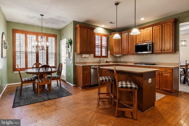 kitchen featuring a center island, an inviting chandelier, wood-type flooring, decorative light fixtures, and appliances with stainless steel finishes