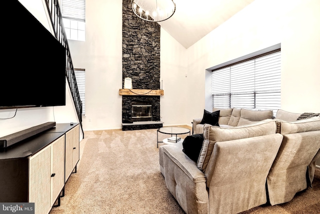 living room with a fireplace, high vaulted ceiling, light colored carpet, and an inviting chandelier